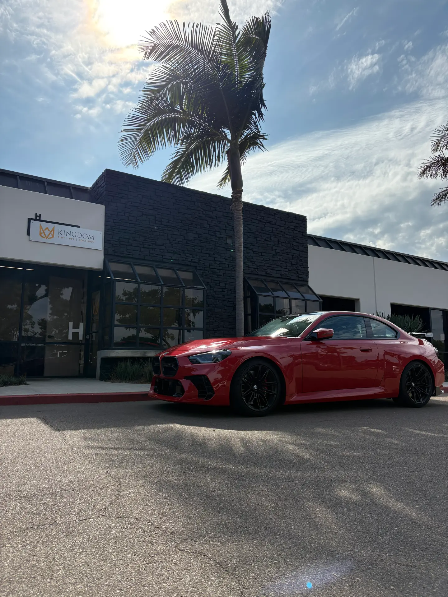 Glossy red BMW parked outside the Kingdom Tint shop in Carlsbad
