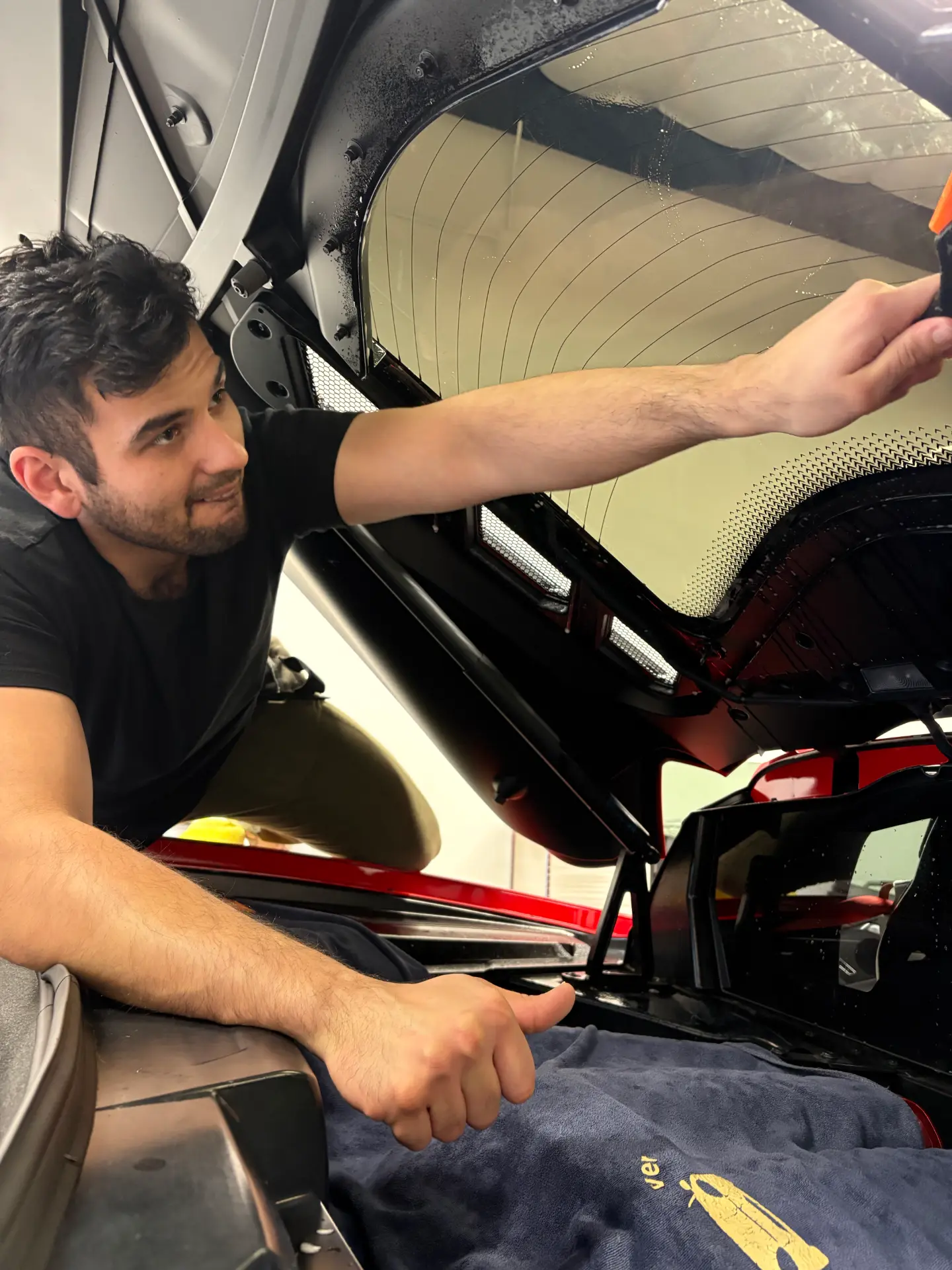Kingdom Tint installer fitting film on a rear hatch glass