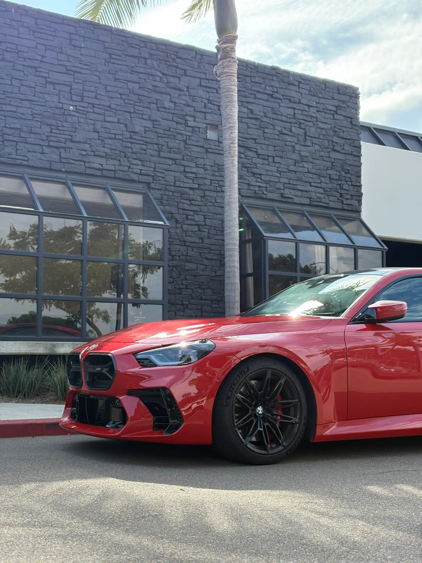 Red BMW M2 parked in front of the Kingdom Tint shop