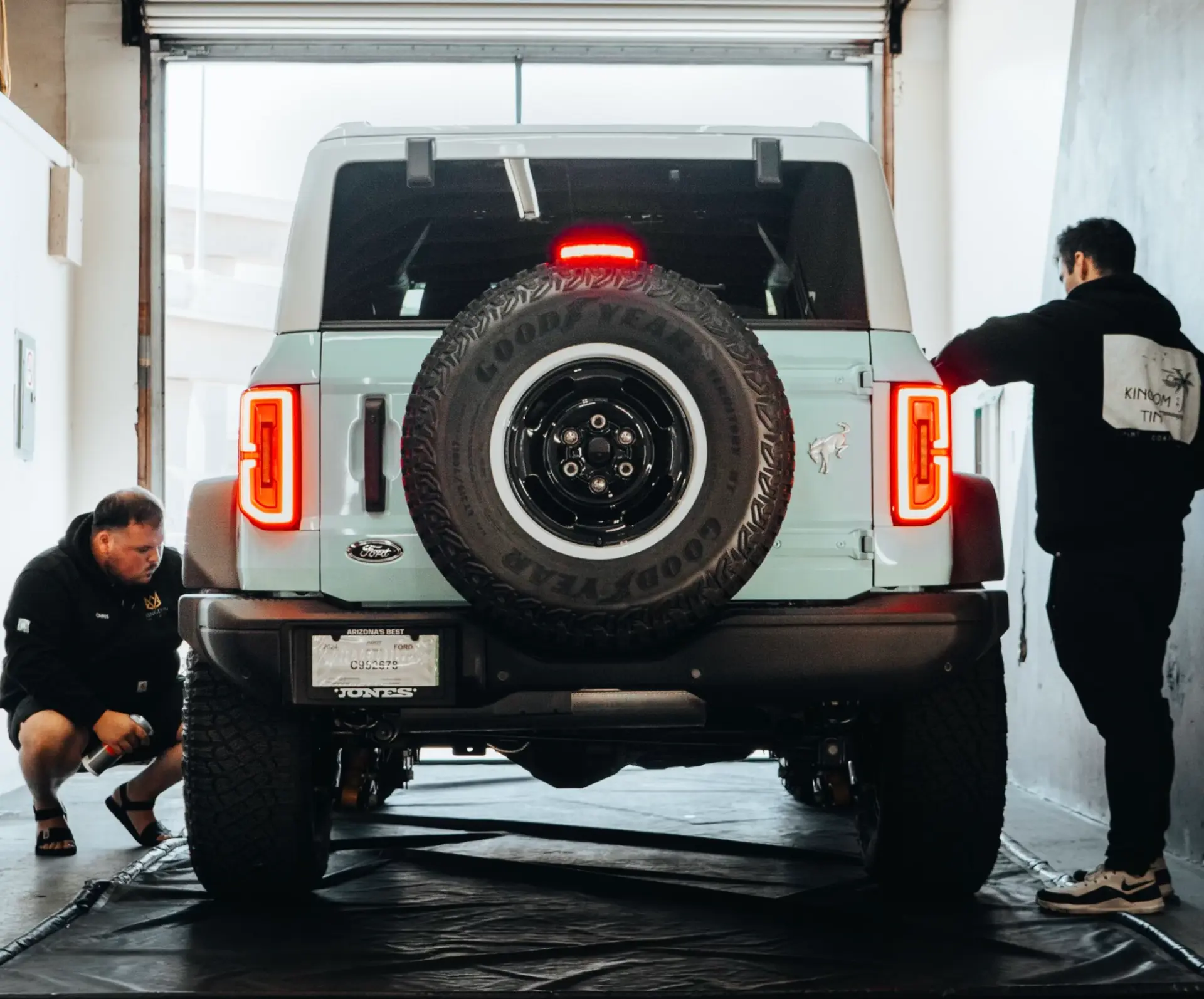 Two Kingdom Tint technicians detailing a Ford Bronco in the shop