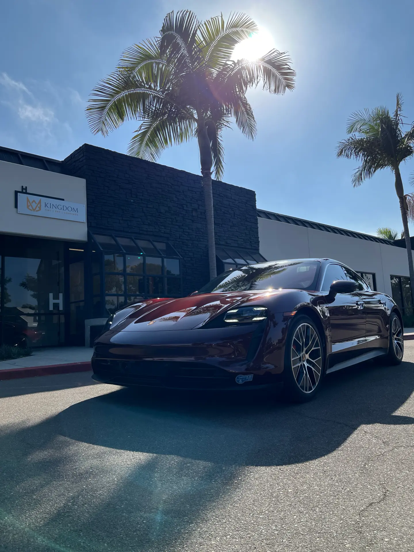 Burgundy Porsche Taycan with tinted windows outside Kingdom Tint