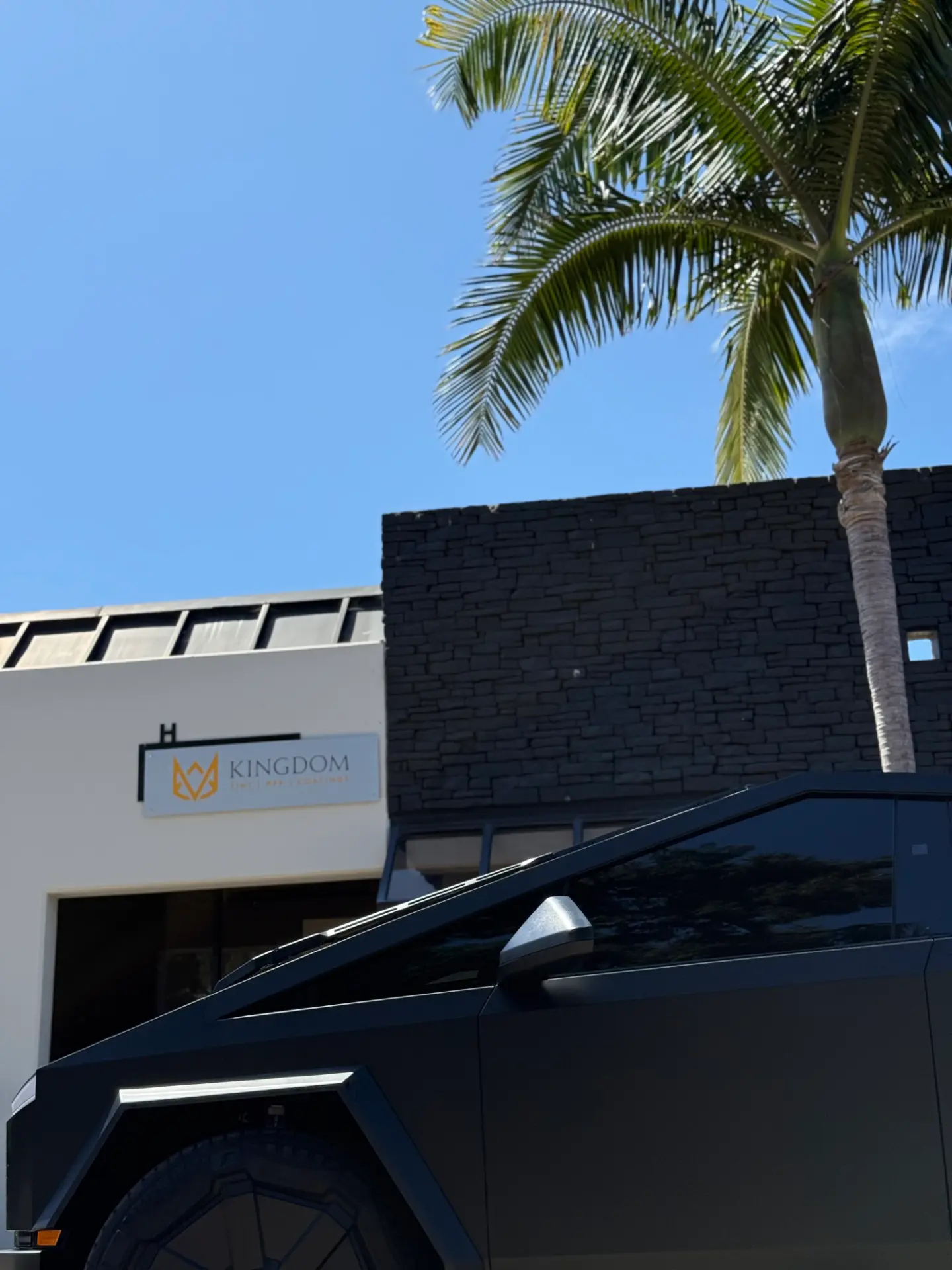 Matte black Tesla Cybertruck with tinted windows outside the Kingdom Tint shop